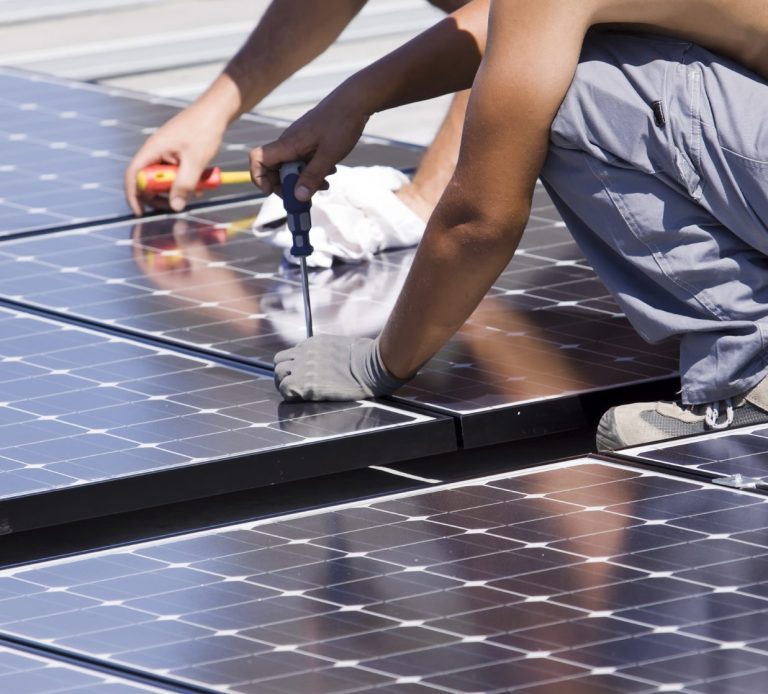 Installation de panneaux solaires sur un toit par un ouvrier.